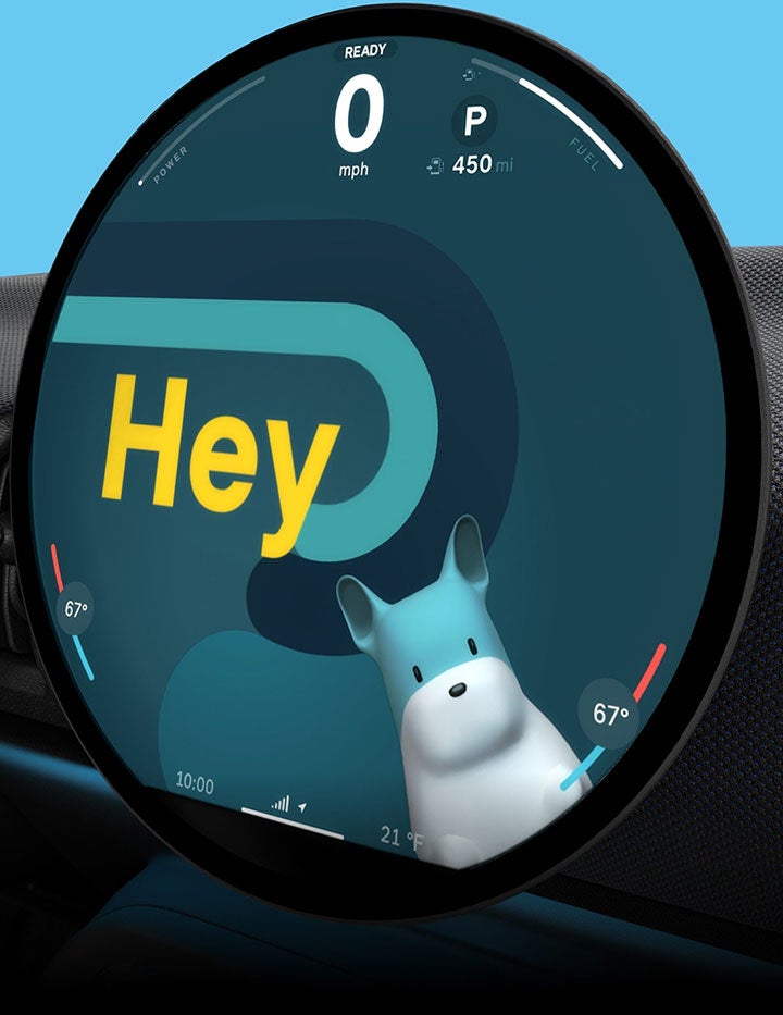 A close-up of the 9.4” round OLED display with Spike on the screen and text reading “Hey” with the surrounding dashboard against a blue background.