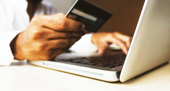 Hand holding credit card in front of open compute | MINI of Madison in Madison WI